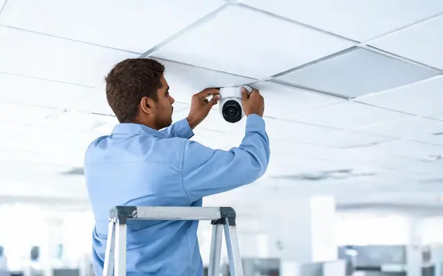 Técnico instalando uma câmera de segurança no teto de um comércio